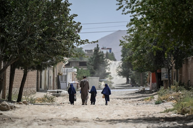 Afghan schoolgirls along with their father walking in the middle of the street.
