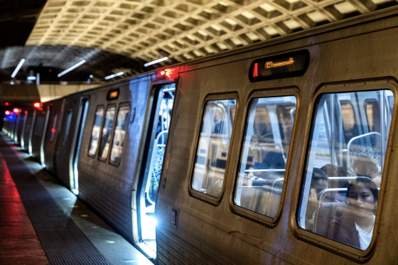 A Metro subway train stopped at a darkened indoor platform.