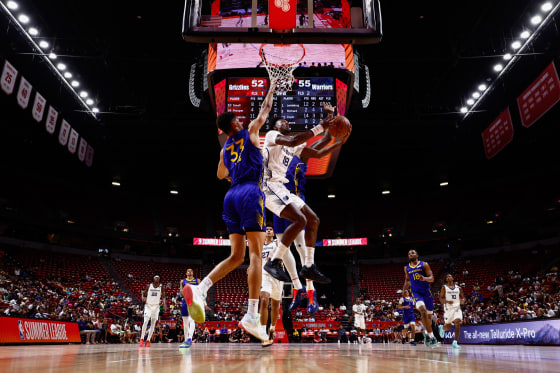 Basketball players rivaling for a ball in front of the basket.