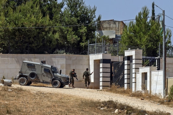 Soldiers stand guard outside a house.
