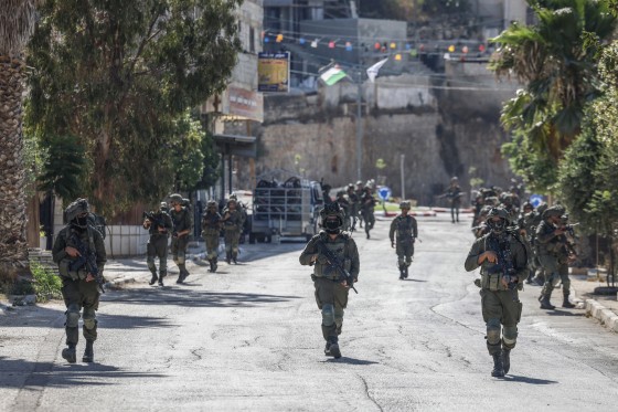Israeli soldiers patrol a street in Qusra.