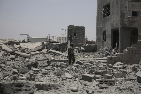 A soldier inspects rubble in the street.
