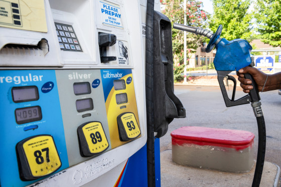 A driver holds a fuel nozzle at a gas pump