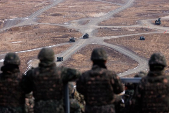 Army soldiers watch a joint live-fire exercise drill.