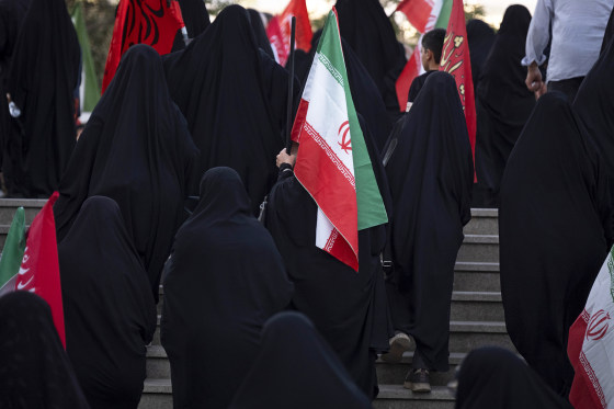 Image: A veiled pro-government supporter carrying an Iranian national flag 