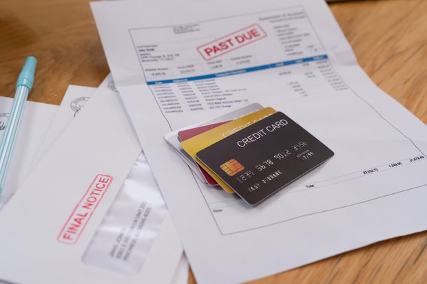 Stack of credit cards on top of an overdue statement of account with a red stamp payment past due notice. 